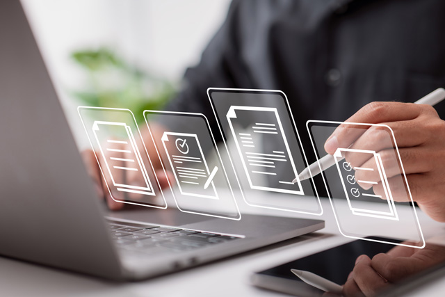 Eine Person bearbearbetet Daten an einem Laptop und prüft die Daten. Hier wird die Antragsbearbeitung des digitalen Bauantrags symbolisch dargestellt.