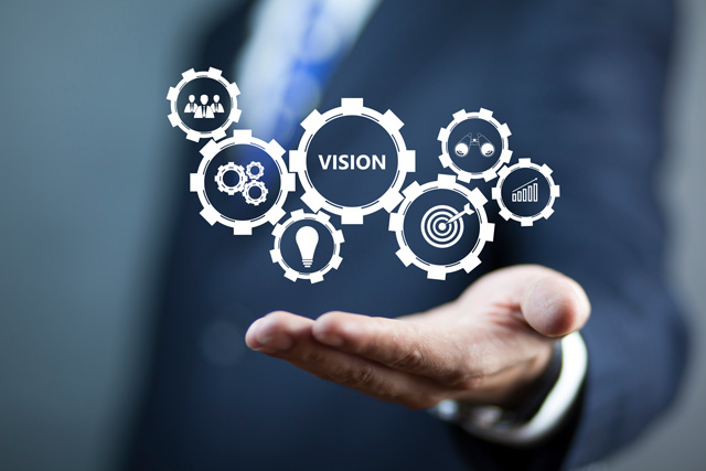 Mehrere ineinandergreifende Zahnräder symbolisieren die Vision der digitalen Baugenehmigung. Die einzelnen Zahnräder haben eigene Icons wie eine Glühbirne oder eine Zielscheibe. Sie deuten auf den Prozess der digitalen Baugenehmigung hin.